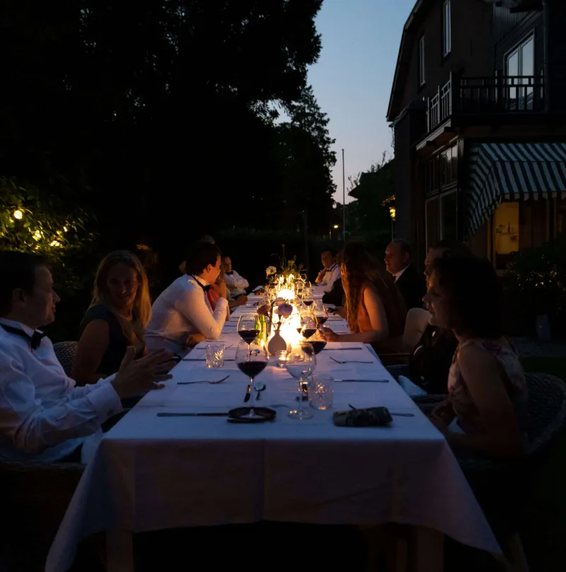 Guests at a long table in the garden in the evening light