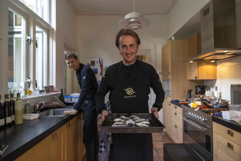 Booy Bakker with a tray of oysters in the kitchen