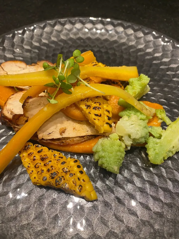 Dish with guinea fowl, corn, romanesco, sweet potato and bunched carrots