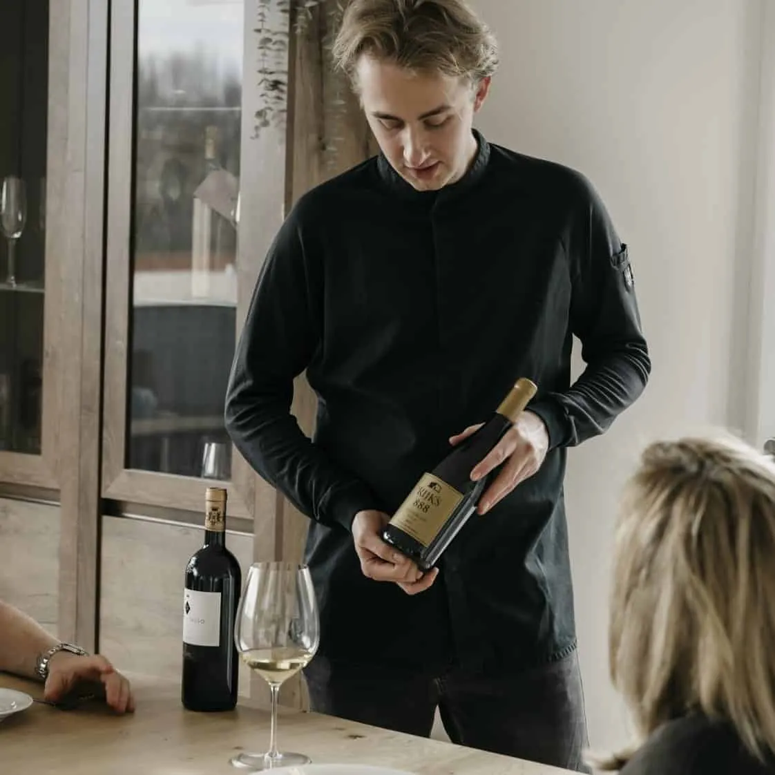 Booy Bakker presenteert een fles wijn aan tafel